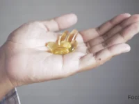 Uma mão segurando cápsulas de Ômega 3, representando suplementos e cuidados com a saúde.